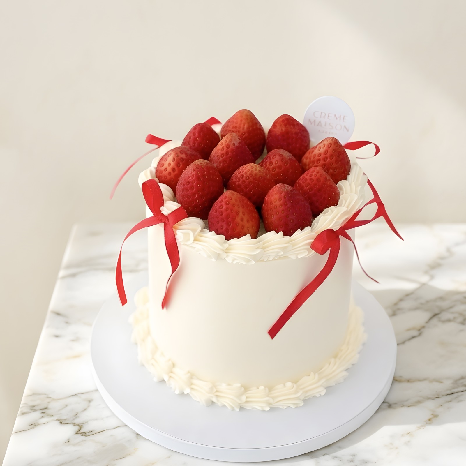 White frosted cake topped with fresh strawberries and red ribbon decorations