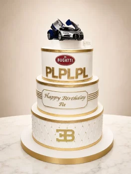Three-tier white and gold birthday cake with a blue-silver Bugatti toy car on top; Bugatti logo and a 'Happy Birthday Pa' plaque on the middle tier.