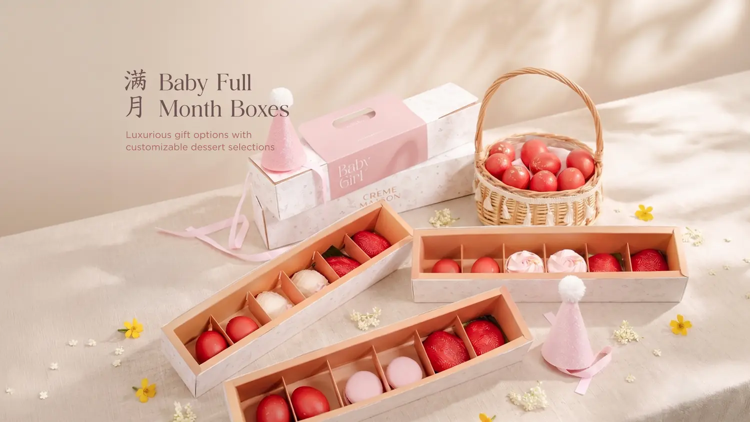 Promotion image for Baby Full Month Boxes: pastel gift boxes with pink accents and a wicker basket of red confections on a beige table.